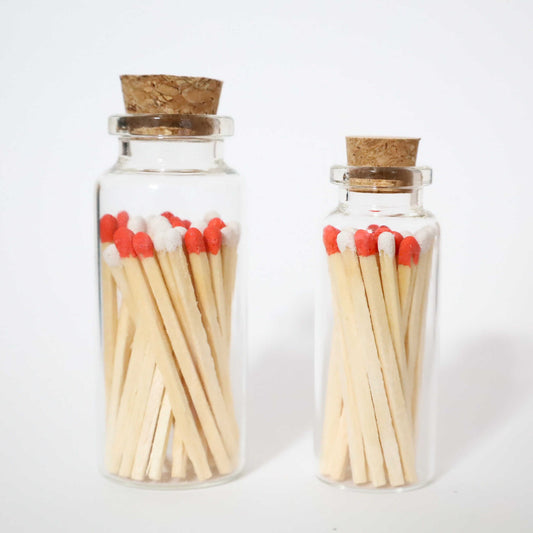 1 small glass bottle and 1 bigger glass bottle with cork cap with red and white safety matches inside