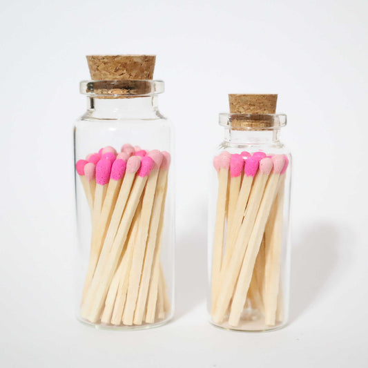 1 small glass bottle and 1 bigger glass bottle with cork cap with hot pink and baby pink safety matches inside